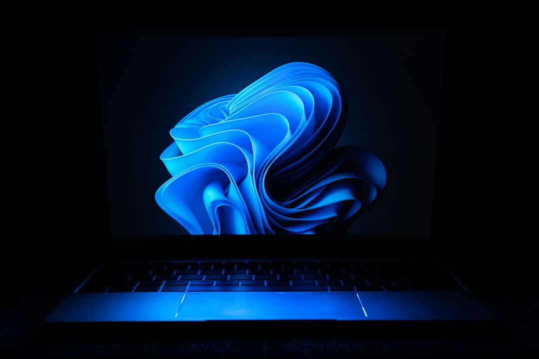 A laptop with a glowing Windows 11 interface on the screen in a dark environment